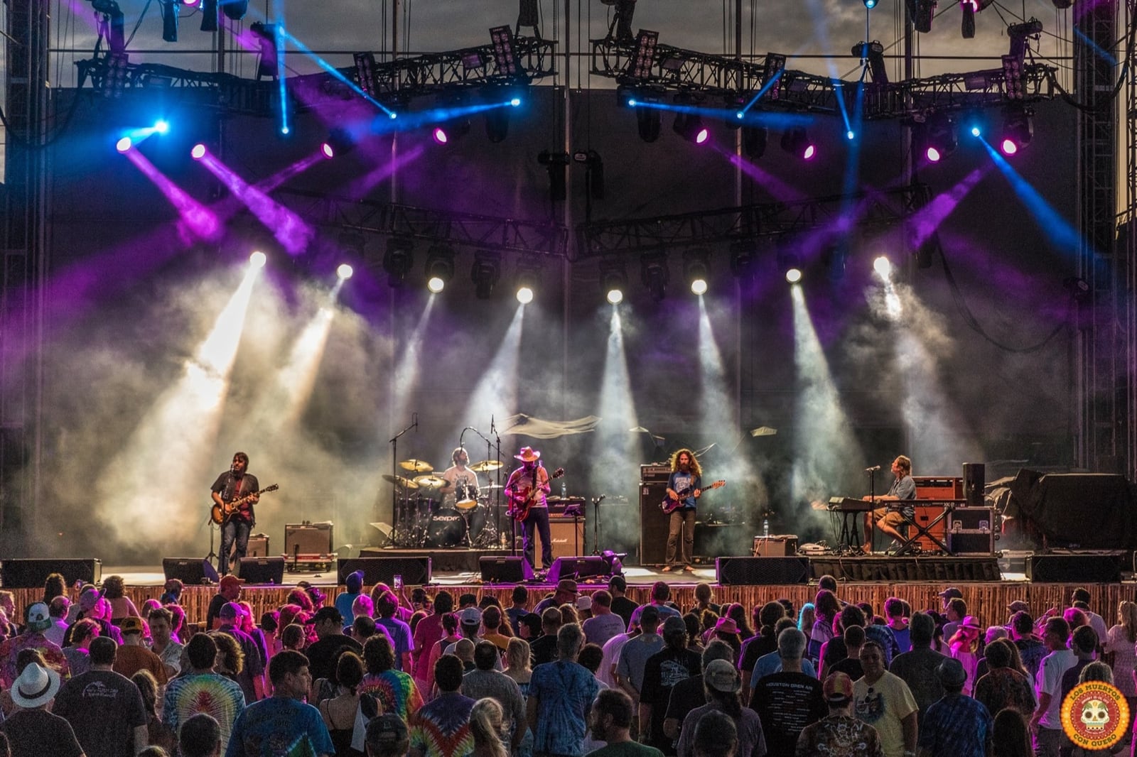 Nathan Dale and the Jackie Greene band performing beneath a large lighting rig before a festival crowd in 2017