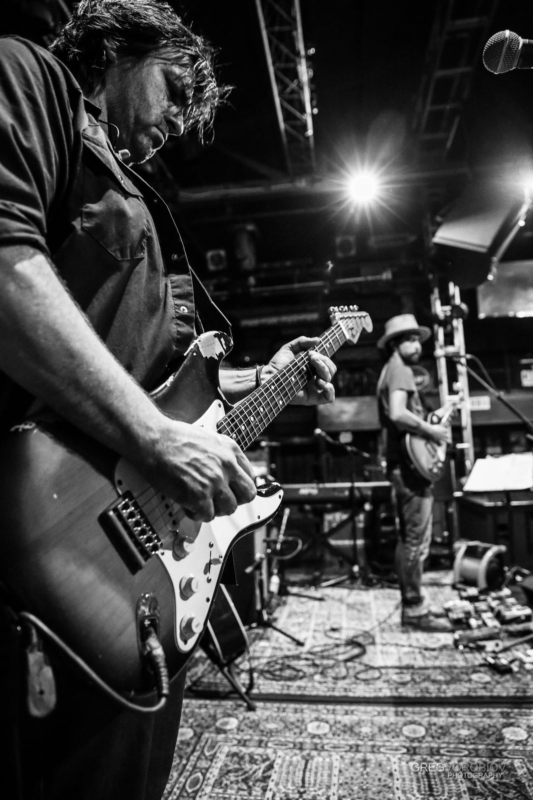 Nathan Dale playing guitar in the foreground with Jackie Greene onstage at the Troubadour in 2015