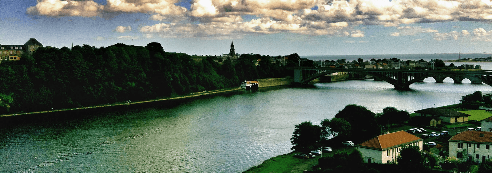 A river, arched bridge, town, and distant water