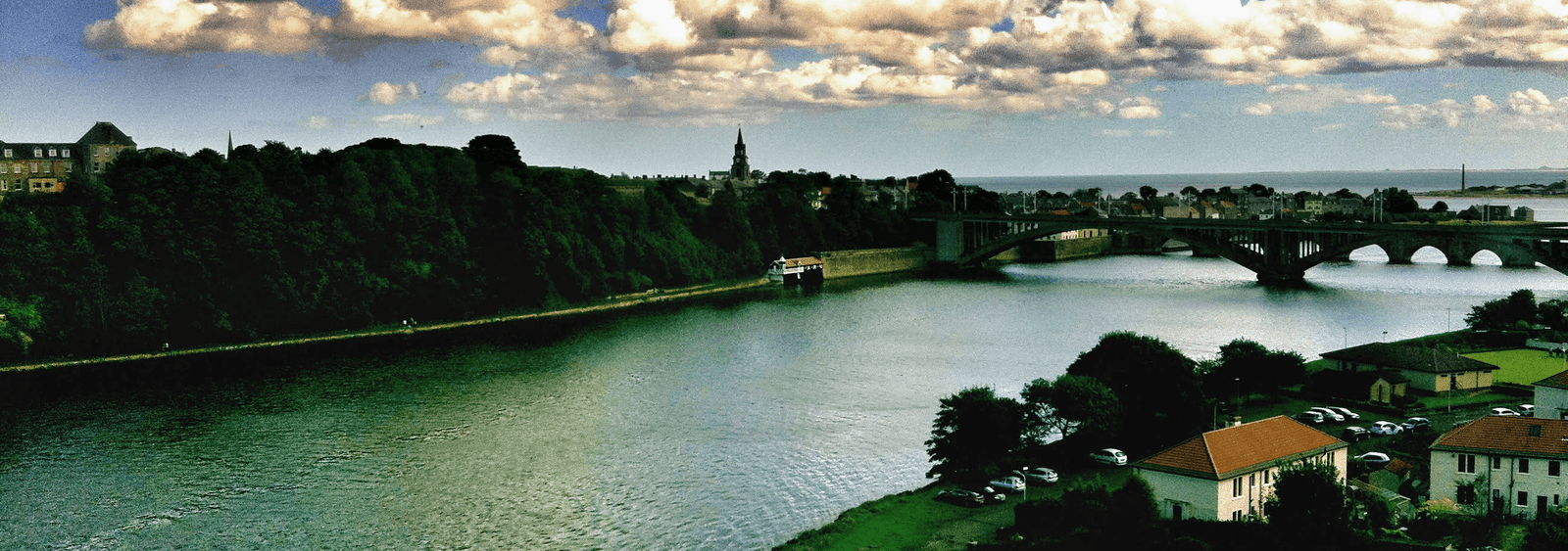A river, arched bridge, town, and distant water