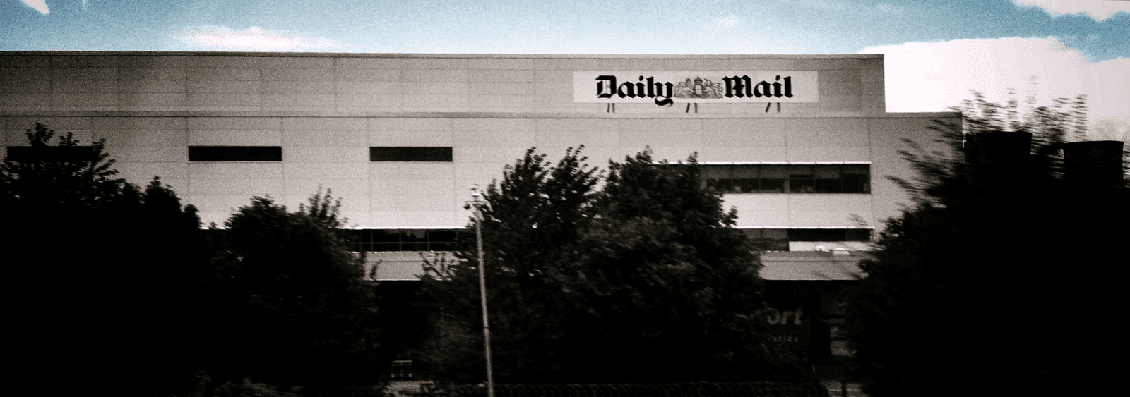 The Daily Mail building seen past trees from a moving vehicle