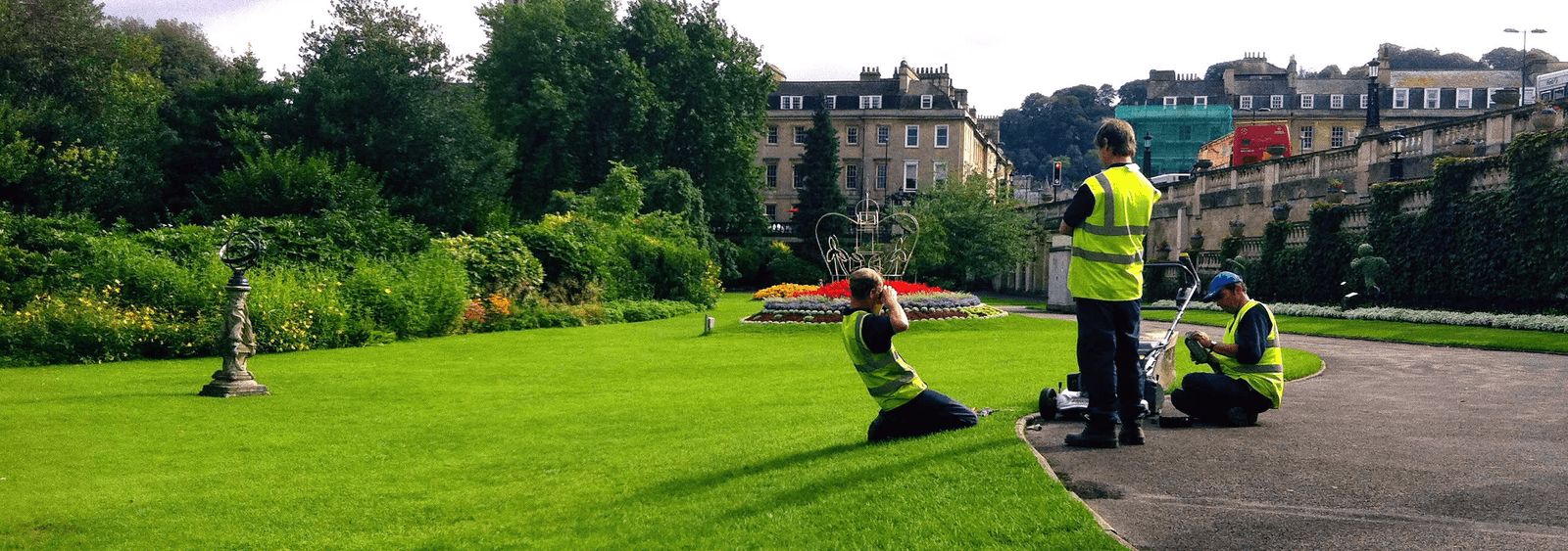 Three groundskeepers beside a formal city garden